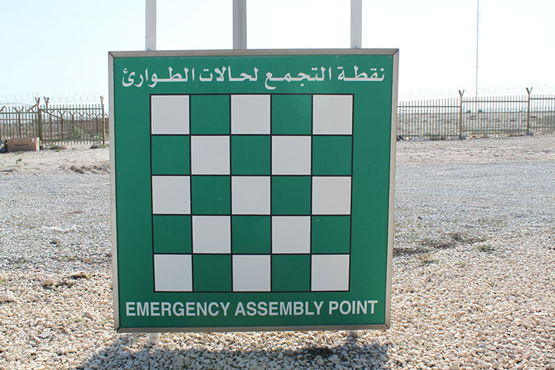 Large green and white checkerboard sign representing an emergency assembly point for Primer for Risk Management blog post article by ADRIDEN Global Inc.